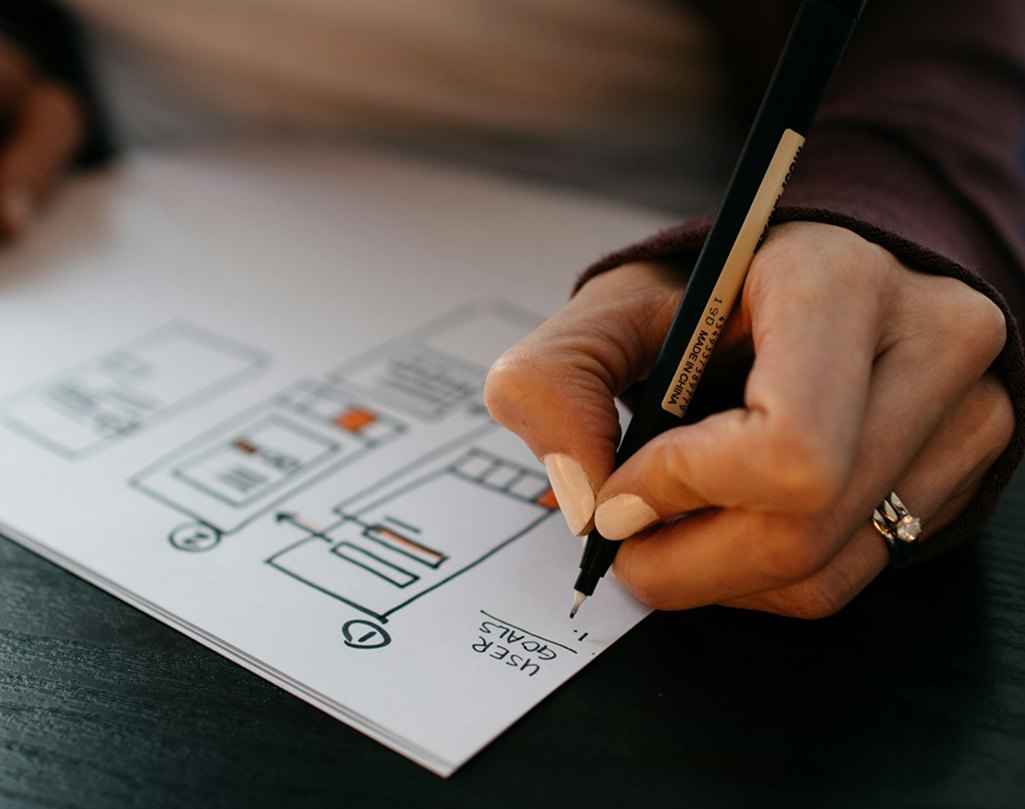 Designer sketching user flows and journey notes on paper